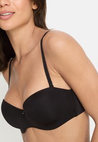 Zwarte gewatteerde strapless bh met verstelbare dunne bandjes, gladde stof en een naadloos ontwerp. Voorzien van een haaksluiting op de achterkant.