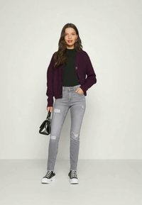 Cardigã roxo, blusa preta, jeans cinza rasgados e ténis pretos. Acessórios incluem uma pequena mala preta. Texturas suaves, estilo casual.