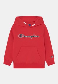 Roter Champion-Hoodie mit vornem Kängurutasche, Logo, das über die Brust gestickt ist, und kleinerem Logo am Bündchen des linken Ärmels.