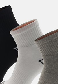 Drei Paar gerippte Baumwollsocken in Schwarz, Weiß und Grau mit kontrastierenden orangefarbenen Akzenten an den Bündchen und einem schwarzen Logodetail.