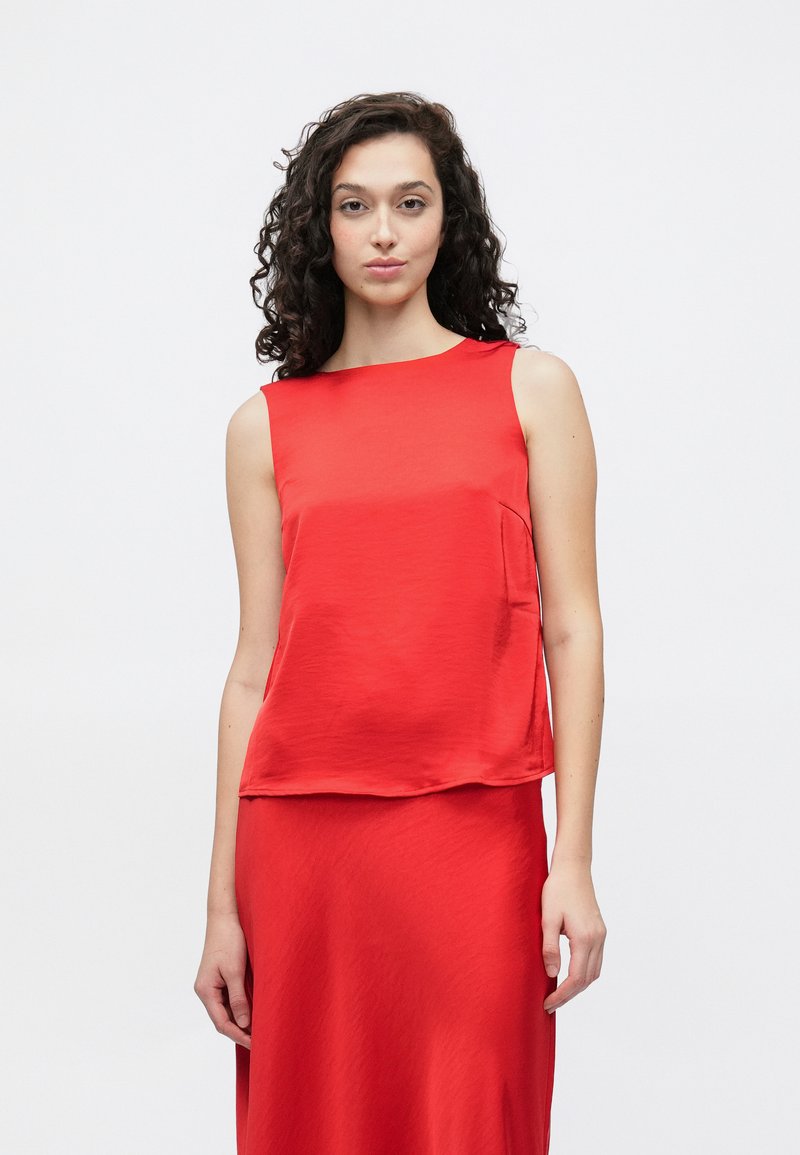 Červený tielkový top s mierne voľným strihom, vyrobený z hladkej látky. Jednoduchý okrúhly výstrih a jemný detail bočného vrecka.