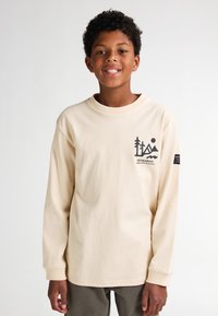 Tricou crem cu mânecă lungă, cu decolteu rotund și imprimeu grafic pe piept. Are manșete ribbate și un logo pe mânecă.