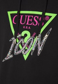 Sudadera negra con un gran gráfico de triángulo verde y texto rosa. "ICON" en strass se muestra de manera prominente en el centro.