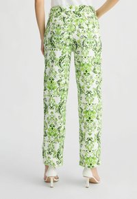 Witte broek met ingewikkelde groene paisley- en bloemenpatronen, met een ontspannen pasvorm en een zoom die de enkels raakt. Draag het met witte hakken.