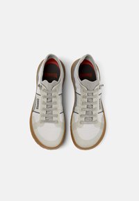 Gray and white athletic shoes with a mesh upper, textured accents, rubber sole, and laces, featuring "Camper" logo on the side and insole.