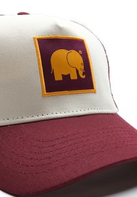 Bordeaux-rot und beige Kappe mit einer strukturierten Oberfläche. Besitzt einen quadratischen gelben Aufnäher mit einer kleinen Elefantenstickerei an der Vorderseite.