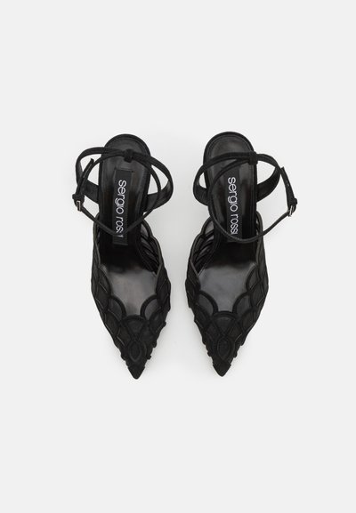 Sandales à talons noirs avec des orteils pointus et de délicates brides autour de la cheville. Présente un dessus texturé avec un design scallopé complexe et un intérieur lisse.