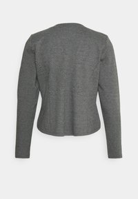 Svart och vit herringbone-mönstrad jacka med långa ärmar, figursydd passform och kortad nederkant. Texturerad tyg med inga synliga knäppningar.