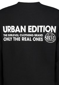 Schwarzer Sweatshirt mit großem weißen Text: "URBAN EDITION DIE SUBLEVEL BEKLEIDUNGSMARKE NUR DIE ECHTEN" und einem runden Logo.
