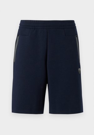 Navyblauwe shorts van zacht materiaal, voorzien van een geribde tailleband, zijzakken met rits en een klein logo-opdruk op de linkeronderkant van het been.