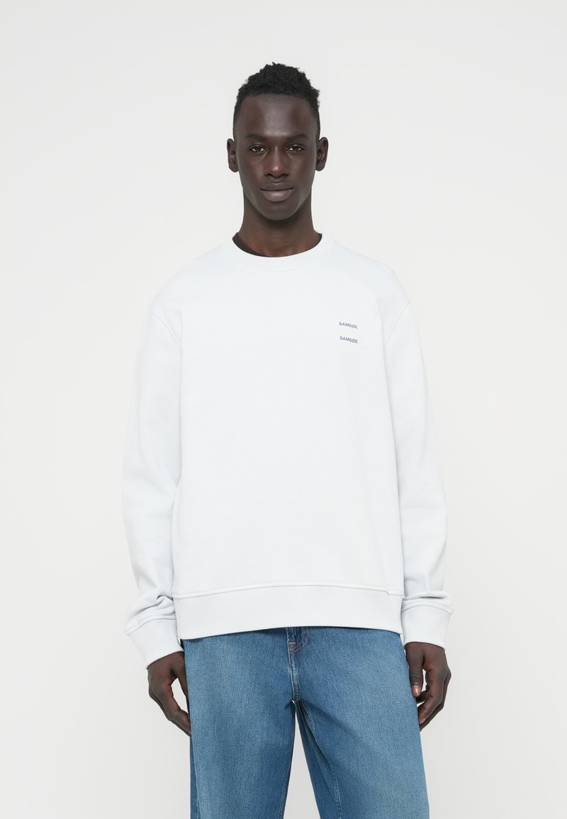 Ανοιχτό γκρι φούτερ από βαμβακερό μείγμα με ριμπ μανσέτες και τελείωμα. Διακοσμημένο με μικρά μαύρα λογότυπα μάρκας στο στήθος. Φοριέται με μπλε τζιν.