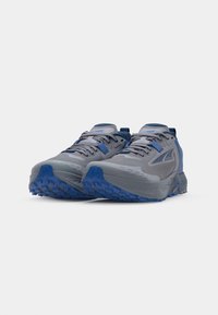 Grijze hardloopschoenen met een gestructureerde mesh bovenkant, blauwe accenten en een robuuste blauwe buitenzool. Opvallend door hun lichte ontwerp en gevoerde zool.