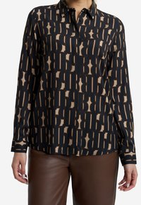 Langärmliges Hemd mit Knopfverschluss in Schwarz und Beige mit geometrischem Muster. Hergestellt aus weichem Stoff, mit spitzem Kragen und geradem Saum.