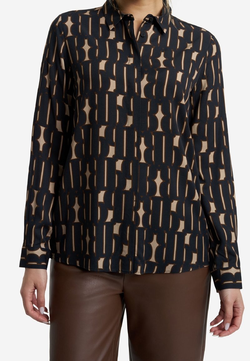 Langärmliges Hemd mit Knopfverschluss in Schwarz und Beige mit geometrischem Muster. Hergestellt aus weichem Stoff, mit spitzem Kragen und geradem Saum.