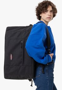 Černý batoh vyrobený z odolné látky, obsahující velkou hlavní přihrádku, dvě zipové kapsy a nastavitelné popruhy pro snadné nošení.