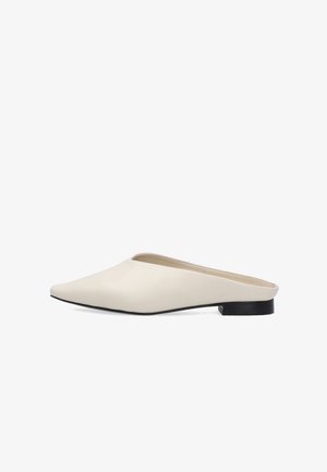 Witte slip-on mule met puntige neus, lage zwarte hak en glad leren bovenwerk tegen een witte achtergrond.
