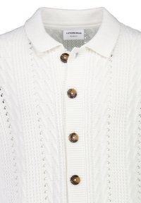 Witte gebreide polotrui met gestructureerde patronen, bruine knopen aan de voorkant en een label "Lindbergh Relaxed Fit" aan de binnenkant van de kraag.