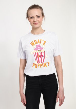 Hvid bomulds T-shirt med et farverigt grafisk design af en lyserød bjørn, der springer ud af en stribet popcornskuffe med teksten "HVAD SKEJER?"