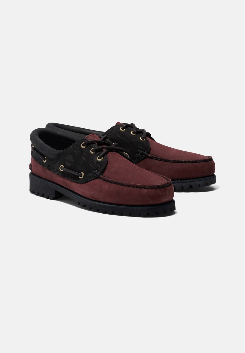Zapatos de hombre tipo mocasín en ante burdeos con detalles en cuero negro, punta redonda, diseño con cordones y suela de goma negra robusta con tracción.