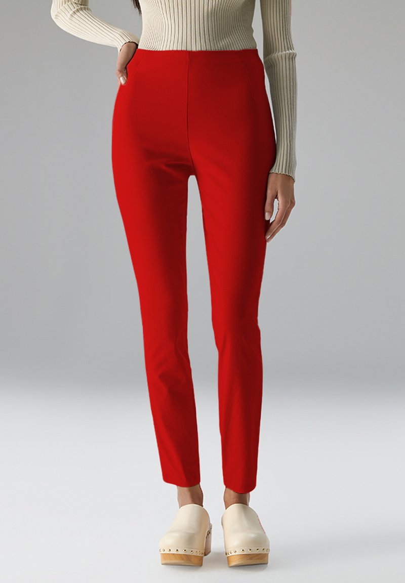 Rode, op maat gemaakte broek met een hoge taille en slim fit. Gemaakt van een gladde stof, gecombineerd met crèmekleurige klompen, die een strakke uitstraling benadrukken.