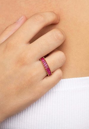 Anillo de oro con una serie de piedras rectangulares verticales en tonos rosa y fucsia, dispuestas en línea recta en una mano. Banda suave y delicada.