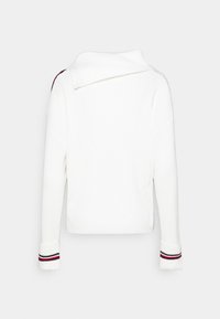 Pull blanc côtelé avec col replié et manches longues. Les poignets présentent des rayures rouges, noires et blanches. Design minimaliste, vue de dos.