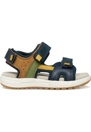 Sandalia para niño al aire libre con correas en azul marino, marrón y verde, cierres ajustables de velcro amarillo y suela de goma blanca con dibujo antiderrapante.