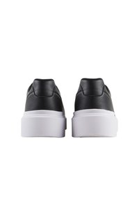 Zapatillas de piel negra con un acabado suave, punta redondeada y suela de goma blanca en contraste. Presentan un diseño de corte bajo y un talón acolchado.