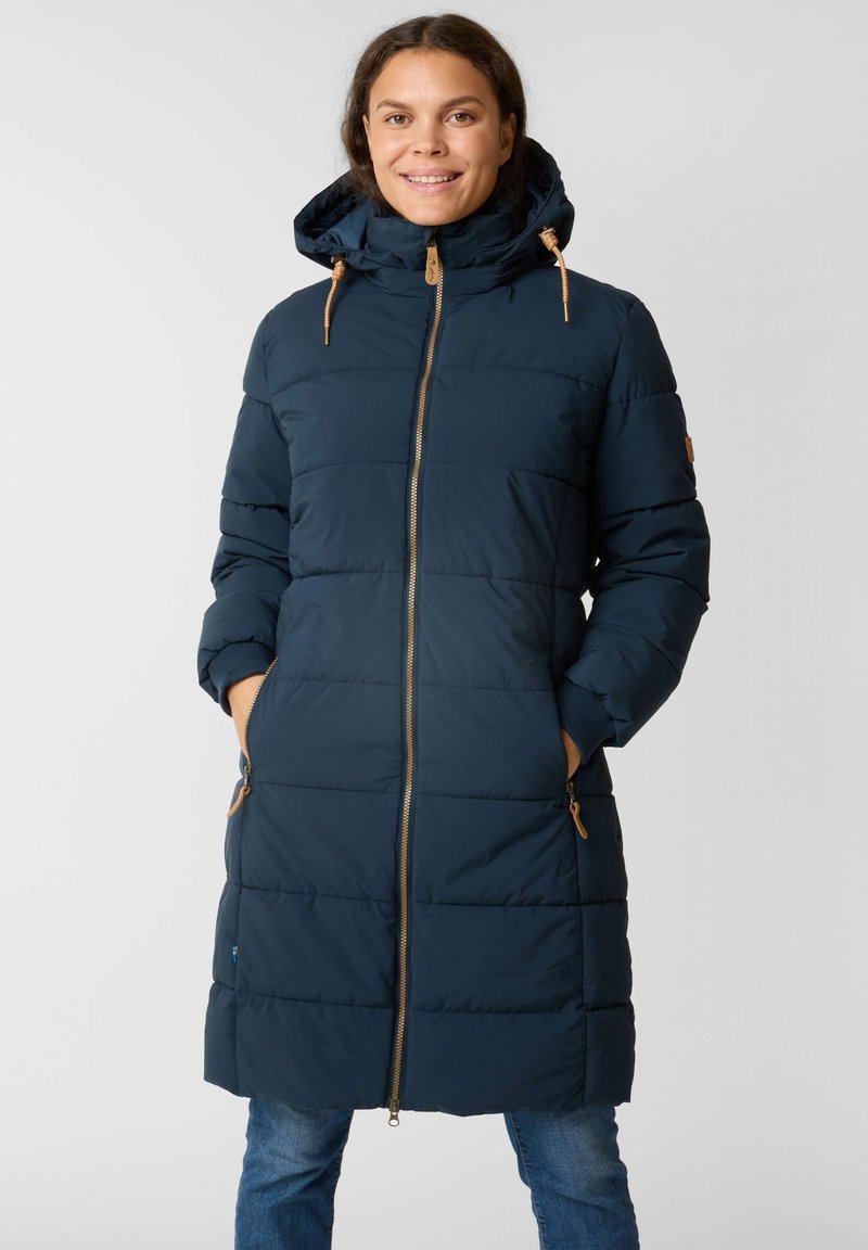 Manteau rembourré bleu marine avec capuche, doté d'une fermeture éclair à l'avant, de poches latérales et de toggles marron. Le design est matelassé avec une coupe mi-genoux.