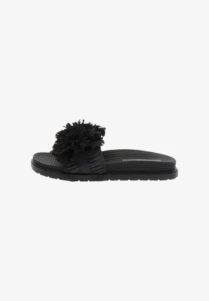 Sandalia slide negra con suela texturizada y una amplia tira con una gran flor de tela esponjosa en la parte superior.