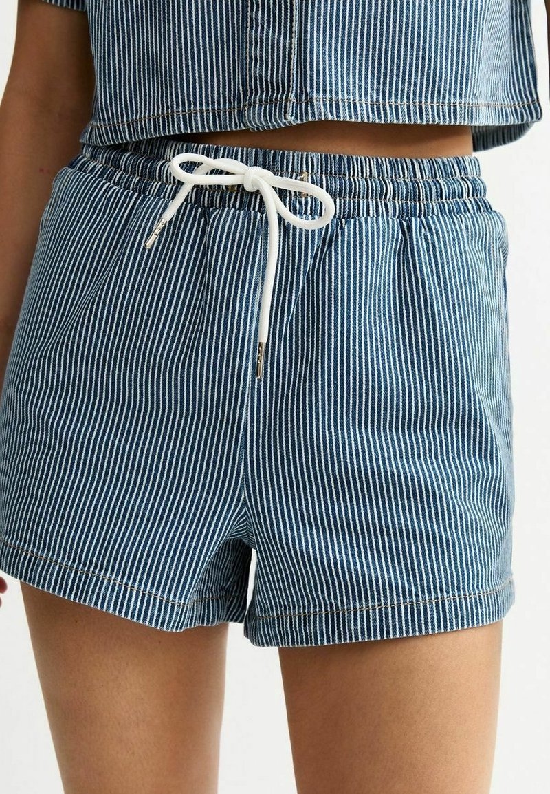 Pantaloni corti in cotone a righe blu con cintura elastica, chiusura con cordoncino e dettagli bianchi. Il tessuto ha una texture liscia e una vestibilità casual.