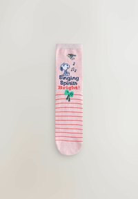 Pink ankle sock with red stripes, featuring illustrations of a dog and musical notes, and the text “Singing Spirits Bright!” with a green bow.