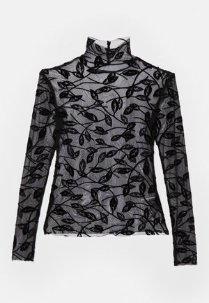 Blusa negra de manga larga con cuello alto, hecha de tela transparente con diseños de hojas de terciopelo en toda su extensión. Cierre con cremallera en la parte posterior.