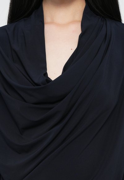 Black draped top with a deep V neckline, featuring soft, smooth fabric that creates flowing folds and a slight sheen.
