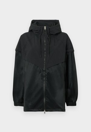 Veste à capuche noire avec fermeture éclair à l'avant, poignets élastiques et design structuré. Caractérisée par des textures de tissu contrastées mates et brillantes.