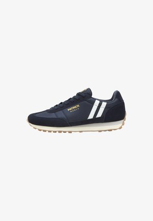 Marineblauwe sneaker met witte zijkanten, beige zool, zwarte veters en een gouden "Patrick Monza" logo op de zijkant.