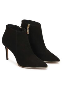 Czarne zamszowe botki za kostkę z wydłużonymi noskami, smukłymi obcasami o dużej wysokości, złotym zamkiem błyskawicznym i cienkim złotym wykończeniem wzdłuż krawędzi podeszwy.