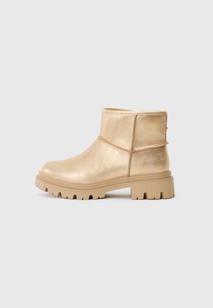 Gold metallic ankle boots with a chunky cream-colored sole, featuring a smooth surface and stitched detailing around the ankle.