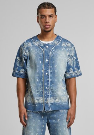 Denim shirt with short sleeves, light blue color, bandana print pattern, front button closure, and contrasting white stitching details.