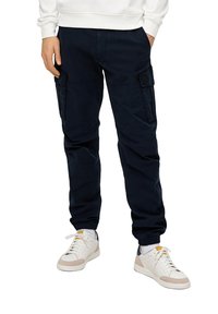 Marine cargobroek met elastische manchetten en zijzakken, gemaakt van zachte stof. Draag ze met witte sneakers met beige en marineblauwe accenten.