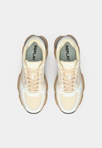Light beige sneakers with mesh and synthetic overlays. Rounded toe, prominent laces, and rubber sole. Accented with silver details.
