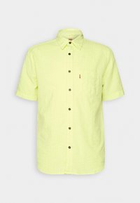 Koszula krótko rękawowa z guziczkami w jasnym żółtym kolorze, z teksturowanym wzorem, posiadająca kieszeń na piersi i ciemne guziki. Klasyczny design kołnierzyka.