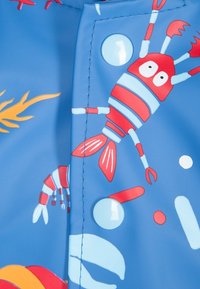 Modrá voděodolná tkanina s červenými humry a bílými bublinkami. Hladký povrch s viditelným akcentem patentního knoflíku.