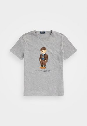 Graues T-Shirt mit kurzen Ärmeln und einer Grafik eines Bären, der vintage-braune Kleidung und orange Schuhe trägt, beschriftet mit "Polo Bear von Ralph Lauren".