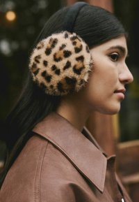 Leopard print faux fur earmuff with a black headband. Close-up of the ear warmer showing soft texture and prominent pattern details.
