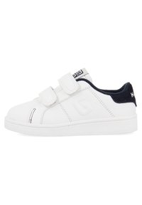 Zapatillas blancas con parte superior de piel suave, cintas de velcro, talón de color marino en contraste y suela blanca texturizada. Presenta detalles de costura mínimos.