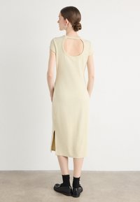 Khaki midi dress with short sleeves, cutout back detail, side slits, and a fitted silhouette. Features smooth, soft fabric and minimalist design.