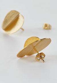 Gull metals stud-øreringer med en teksturert sirkulær skivedesign. Egenskaper inkluderer en push-back lukking og en glatt, reflekterende overflate.