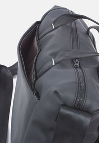 Schwarze Nylon-Duffel-Tasche mit großem Reißverschlussöffnung, ausgestattet mit stabilen schwarzen webbed Griffen und einer glatten, matten Oberfläche.