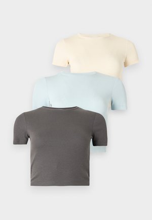 Tre ribbestrikkede korte ermer crop-topper stablet, i mørk grå, lys blå og kremfarger, på en ensfarget hvit bakgrunn.